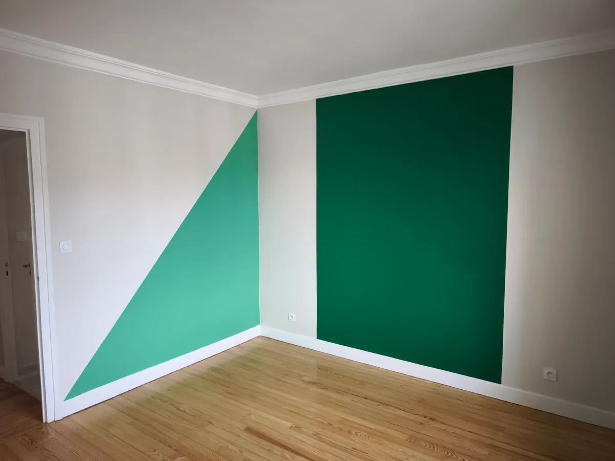 Pièce rénovée avec peinture géométrique verte sur des murs blancs